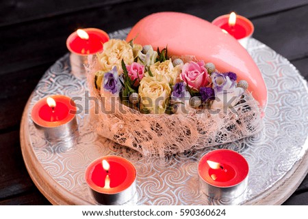 Mirror glaze heart cake dessert on Valentines Day, classic Valentines Day heart-shaped cake with candles and flower decorations.
