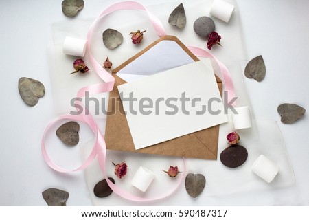 Workspace. Wedding invitation cards, craft envelopes, pink and red roses and green leaves on white background. Overhead view. Flat lay, top view wedding invitation card Templates. 
