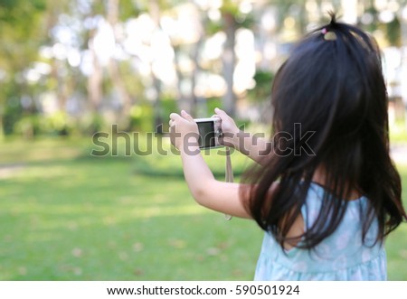 Child girl taking pictures on camera in the garden, Focus at camera