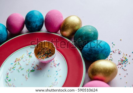 Beautiful colorful easter eggs with confectionery sprinkling and on plate and pink background