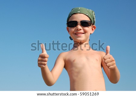 Happy child with thumbs up on blue sky background