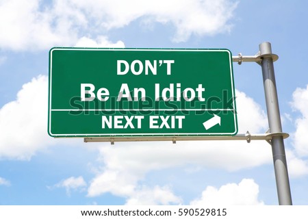 Green overhead road sign with a Don't Be An Idiot Next Exit concept against a partly cloudy sky background.  Royalty-Free Stock Photo #590529815