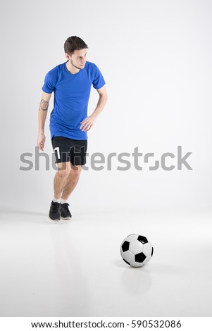 Picture of young soccer player hit the ball football player in blue t shirt black shirts free kick image isolated in studio man watching in right corner