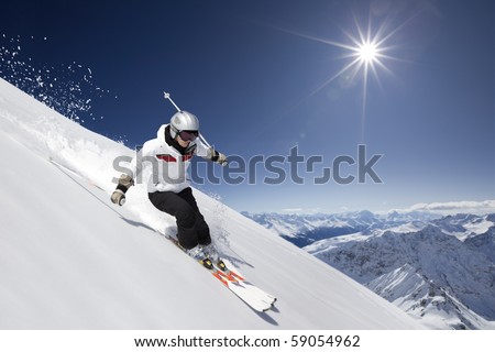 female skier skiing downhill with sun and mountains.