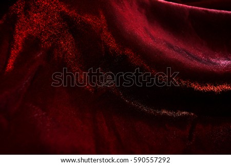Close-up photo of the drape flowing red shimmering textile to background.