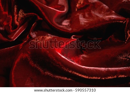 Photo of the drape red shimmering fabric texture to background.
