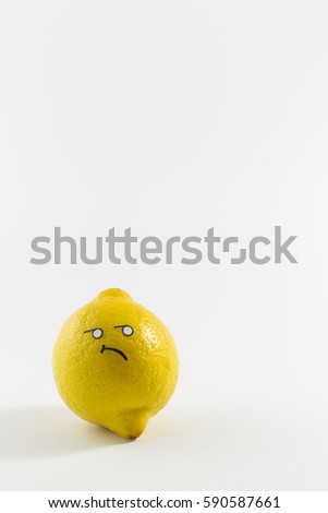 A fresh yellow lemon with sour looking cartoon style face on white background