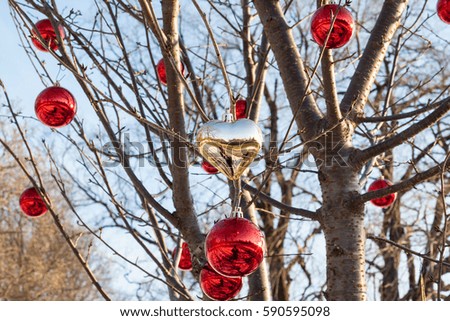 Gold heart surrounded by shiny red holiday ornaments in a tree in Brooklyn, New York
