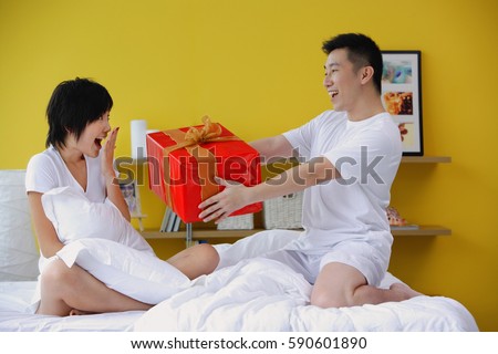 Man giving woman present in bedroom
