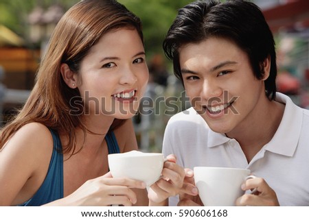 Couple in cafe having coffee, smiling at camera