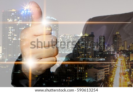 Double exposure of The business man holds thumb up and night city building background