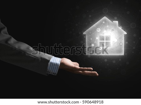 Male hand holding on the palm of a glowing house icon or symbol