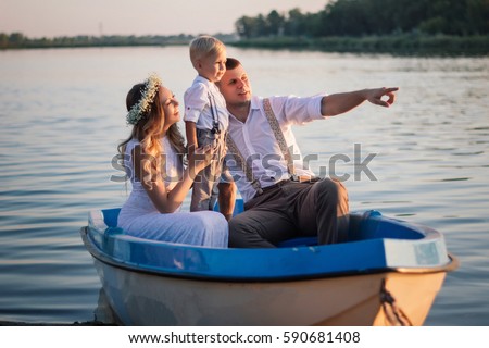 Happy family sitting in the boat. photo shoot near the pond. Beautiful mother, father and child. Camping with the whole family. feast for the senses. Communication with your child.
