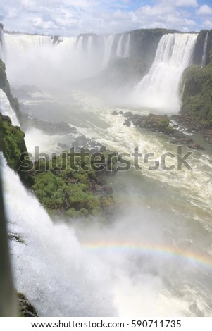 Iguazu falls in a vertical picture, with a rainbow from Brasilian Side, in a sunny day