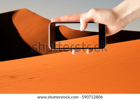 Woman on vacation takes a picture smartphone in the desert.