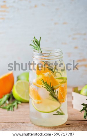 orange lemonade with rosemary and ice. wooden rustic background