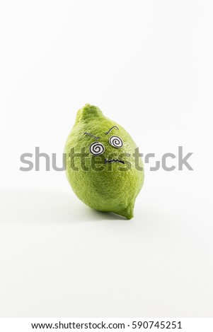A fresh green lemon with sour looking cartoon style face on white background