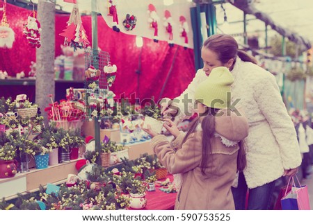 girl with mother choosing mistletoe decorations for Christmas. Focus on woman