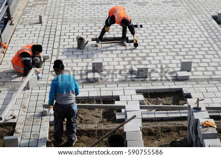 Workers install paving slabs in the courtyard (paving)