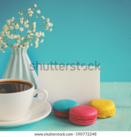 Blank paper card with cup of tea and vase in flower and macaroons for woman day.