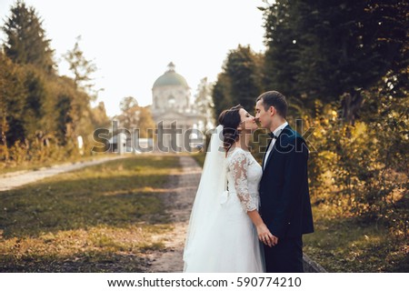 gorgeous wedding couple . The happinest brides embracing near castle. Groom and bride embrace on a background of the castle. couple in love against the backdrop of an old church
