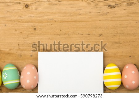 Easter holiday background. Pastel coloured decorated easter eggs with a blank white label on a wooden background