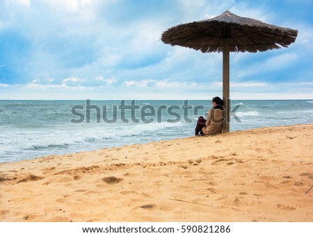 girl sitting under sunshade looking afar the blue seas