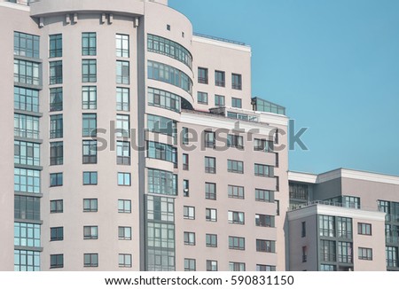 Multi-story office building beige color with lots of glass windows on a background of pure blue sky. Newly built office space for rent