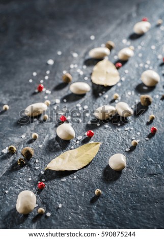 White beans and spices are scattered randomly on a black stone table from slate. Space for text.