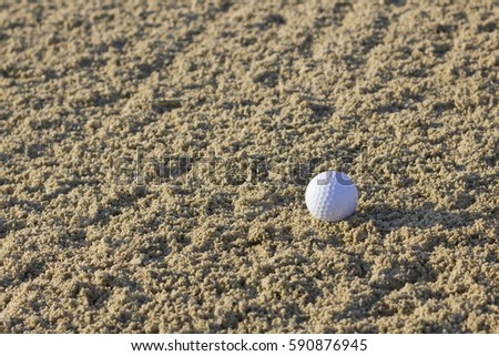 Lonely golf ball in sand bunker.