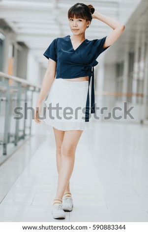 Portrait of young happy Asian girl standing indoor