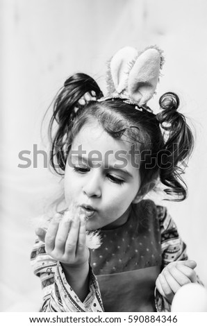 little girl 2 - 4 years in a red dress draws intently the pictures on the eggs with watercolors . at the head of the child ears of a rabbit preparing for Easter black and white , monochrome