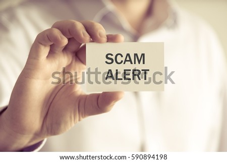 Closeup on businessman holding a card with text SCAM ALERT, business concept image with soft focus background and vintage tone