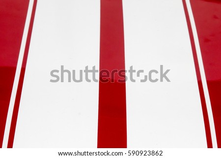 White pin stripes full frame on the hood of a bright red car