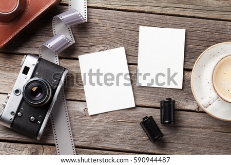 Vintage camera, blank photo frames and coffee cup on wooden table. Top view with copy space
