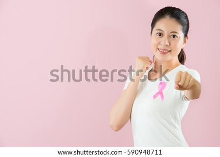 Cheerful and open minded Chinese Asian young girl make a fist elongation of her arms showing the positive faith and fighting for cancer isolated on pink background. medical and health concept.