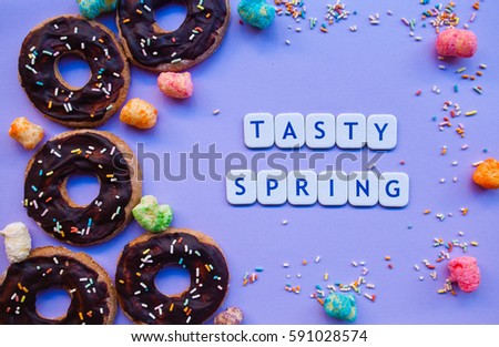 Many glazed chocolate donuts with text tasty spring. Food  background. Delicious biscuits.