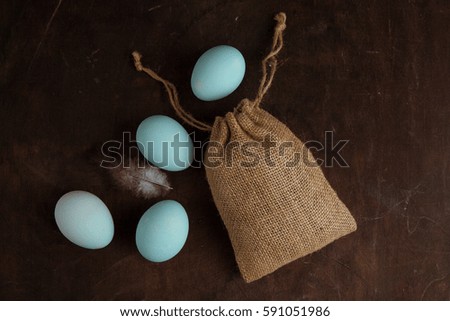 Sack and blue eggs on the wooden background