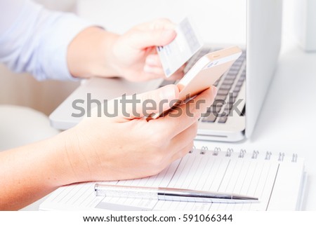 Someones hands holding mobile phone and credit card, making on-line payment