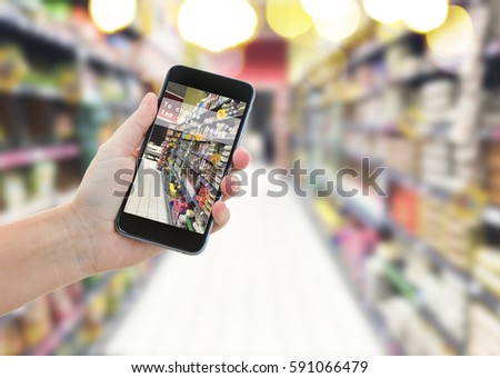 someones hand holding mobile smart phone with augmented reality app in supermarket shop