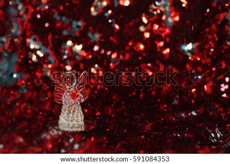 little glass angel with heart on dark red shining abstract background. recognition, Valentine's day concept. symbol of love and tenderness. copy space