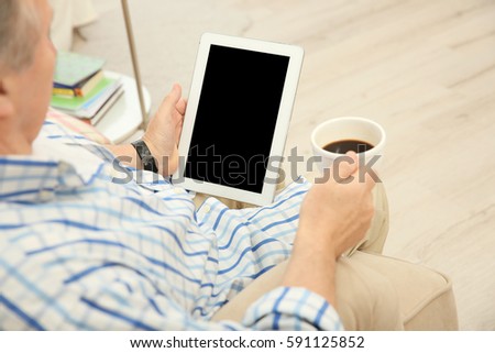 Senior man making video call from tablet computer at home