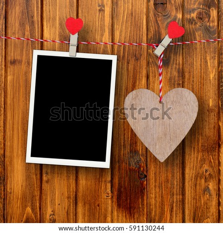 Wooden heart and empty photo frame on a rustic wooden background as love concept for valentines day