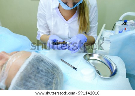 Blonde girl European appearance, professional engaged in reconstruction of eyebrows responsibly preparing to start work mikrobleyding eyebrows, eyebrows customer focused prepares women to paint