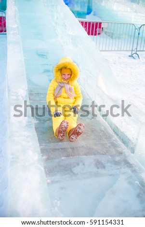 Adorable little girl riding on an ice hill outdoors