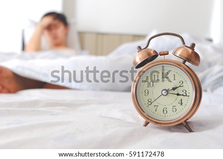 
Antique Alarm Clock.Background Men have insomnia in bed, insomnia, headaches caused by anxiety.Health and medical concepts