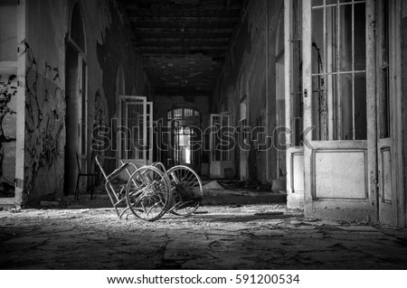View of a room with wheelchair abandoned in the Psychiatric Hospital of Volterra in Tuscany. Italy Processing Black and White. Royalty-Free Stock Photo #591200534