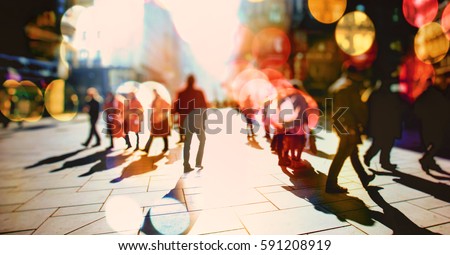Crowd of anonymous people walking on sunny streets in the city 