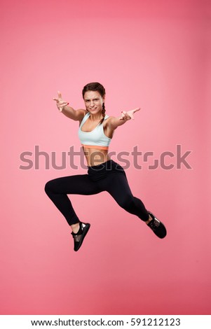 Funny girl in sport clothing smiling and juming like Spiderman