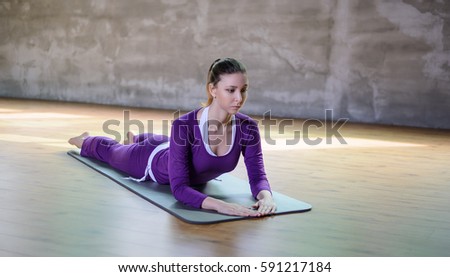 Beautiful athletic young female make yoga Salamba Bhujangasana or Sphinx Pose. Front view.